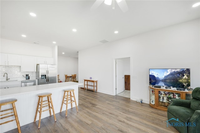 kitchen with appliances with stainless steel finishes, light hardwood / wood-style floors, white cabinetry, and ceiling fan