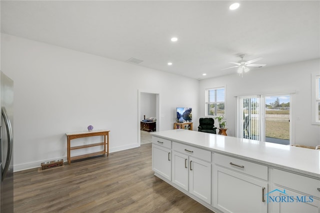 kitchen with white cabinets, wood-type flooring, stainless steel refrigerator, and ceiling fan