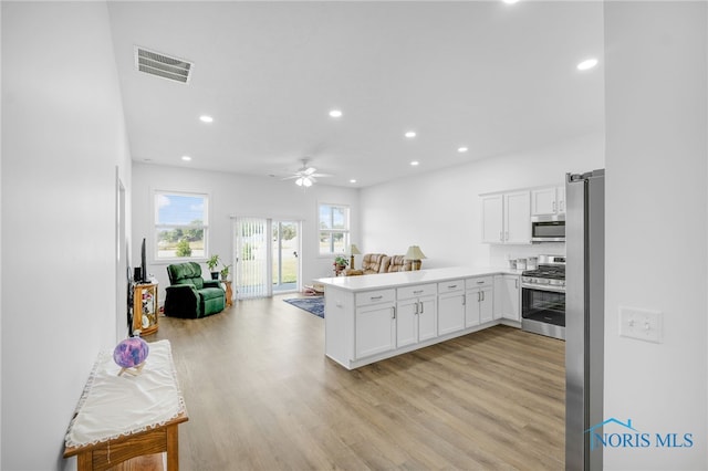 kitchen with light wood-type flooring, ceiling fan, stainless steel appliances, and kitchen peninsula