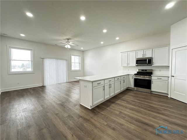 kitchen featuring white cabinetry, appliances with stainless steel finishes, dark hardwood / wood-style floors, and kitchen peninsula