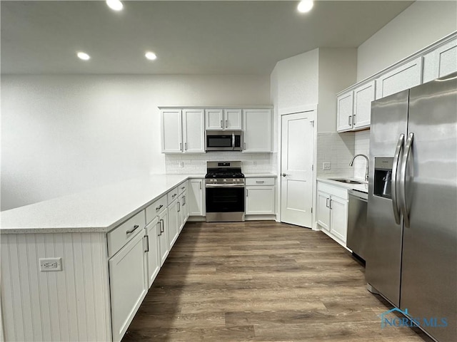 kitchen with sink, backsplash, white cabinets, dark hardwood / wood-style flooring, and stainless steel appliances