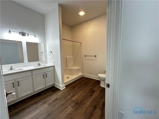 bathroom with toilet, hardwood / wood-style floors, vanity, and walk in shower