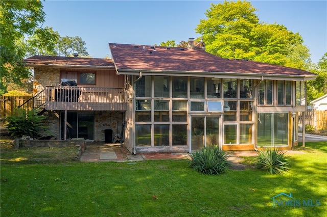 rear view of house featuring a lawn, a sunroom, and a deck