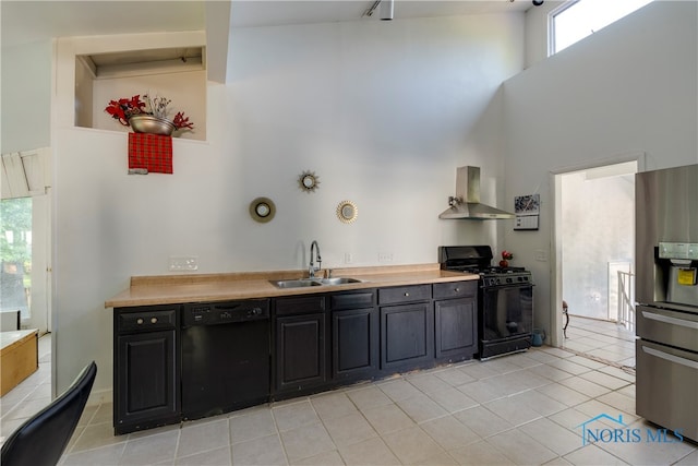 kitchen featuring high vaulted ceiling, a healthy amount of sunlight, black appliances, sink, and wall chimney range hood