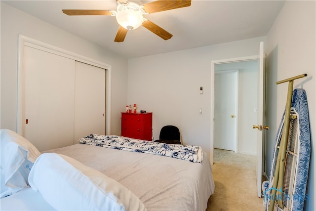 bedroom with light carpet, ceiling fan, and a closet