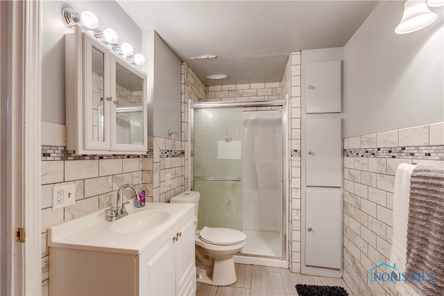 bathroom featuring an enclosed shower, tile walls, toilet, and vanity