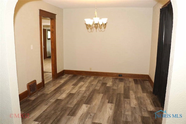 unfurnished room with dark wood-type flooring and an inviting chandelier