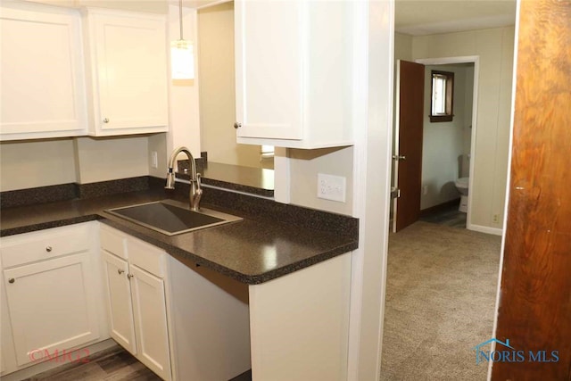 kitchen featuring white cabinets, pendant lighting, dark colored carpet, and sink