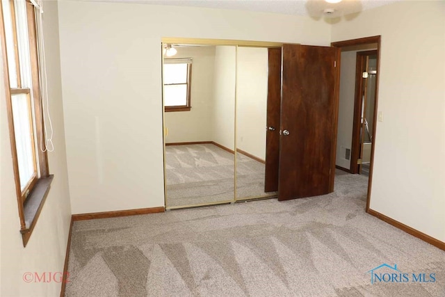 unfurnished bedroom featuring a closet and light colored carpet