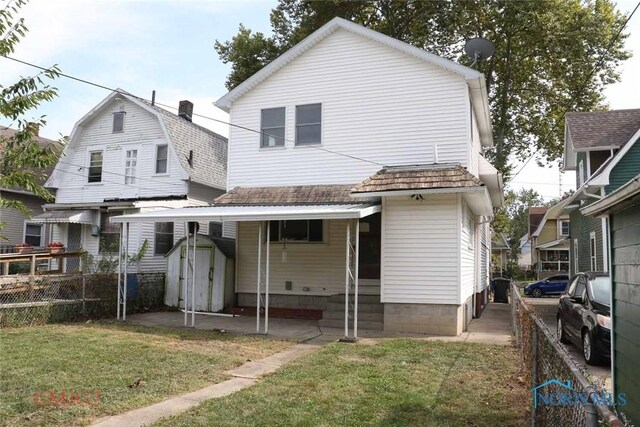 rear view of house with a storage shed and a lawn