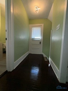 hallway with lofted ceiling and dark wood-type flooring