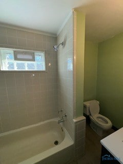 full bathroom featuring tiled shower / bath, vanity, crown molding, and toilet