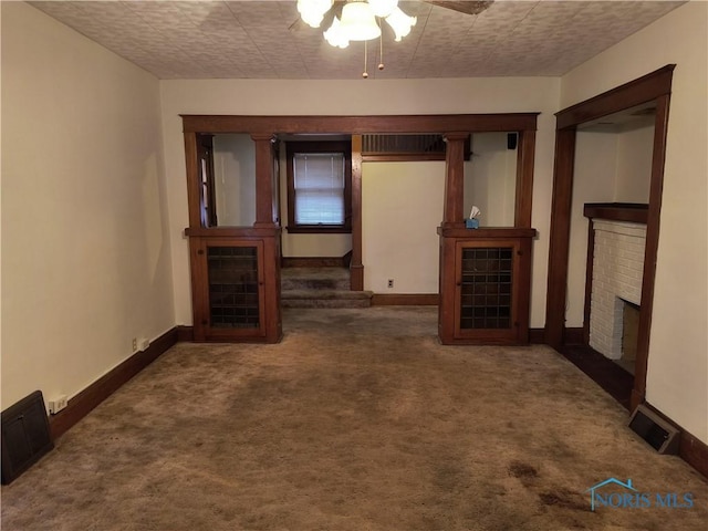 unfurnished living room with a textured ceiling, ceiling fan, dark carpet, and a fireplace