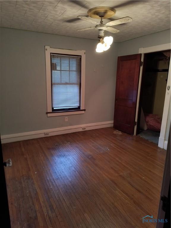 unfurnished bedroom featuring a closet, ceiling fan, and dark wood-type flooring