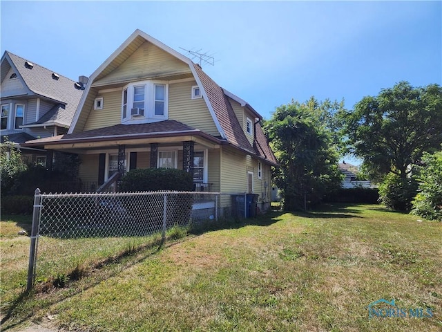 view of front facade with roof with shingles, a fenced front yard, a front yard, and a gambrel roof