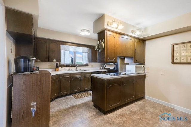 kitchen with kitchen peninsula, dark brown cabinetry, sink, and black stovetop