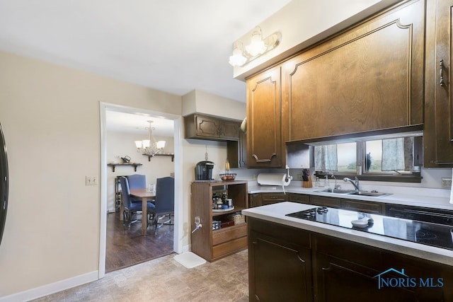 kitchen featuring a notable chandelier, dark brown cabinetry, black electric cooktop, and sink