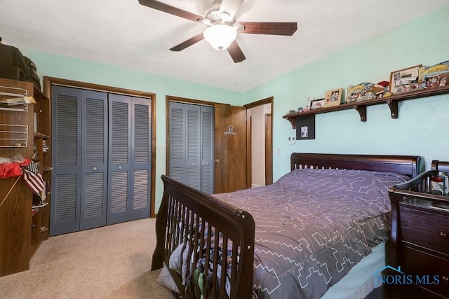 carpeted bedroom featuring ceiling fan and two closets