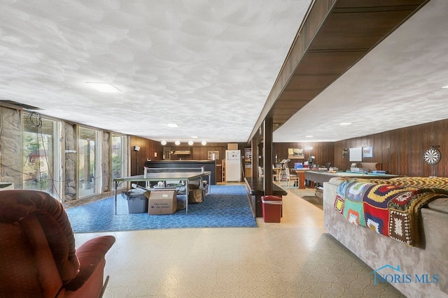 game room with a textured ceiling and wooden walls