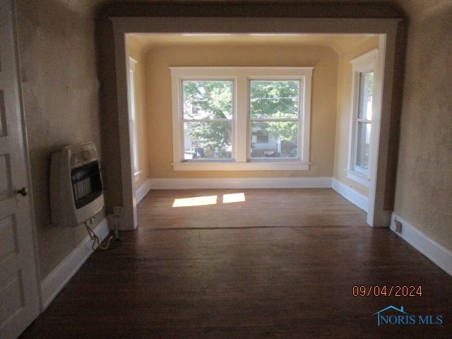 unfurnished living room featuring heating unit and wood-type flooring