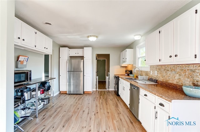 kitchen featuring appliances with stainless steel finishes, white cabinetry, sink, and light hardwood / wood-style flooring