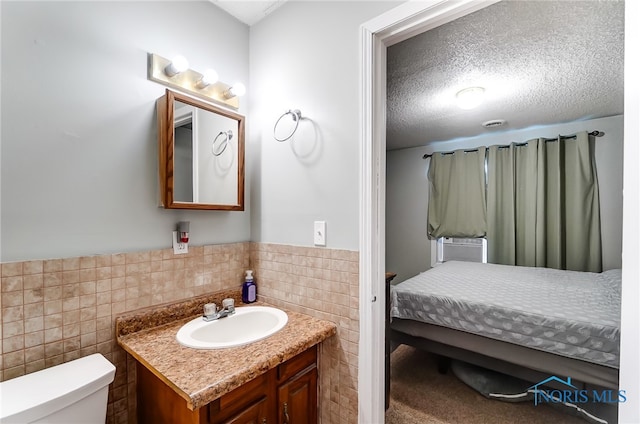 bathroom with tile walls, a textured ceiling, vanity, and toilet