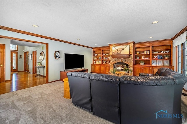 carpeted living room with a textured ceiling, crown molding, built in features, and a fireplace