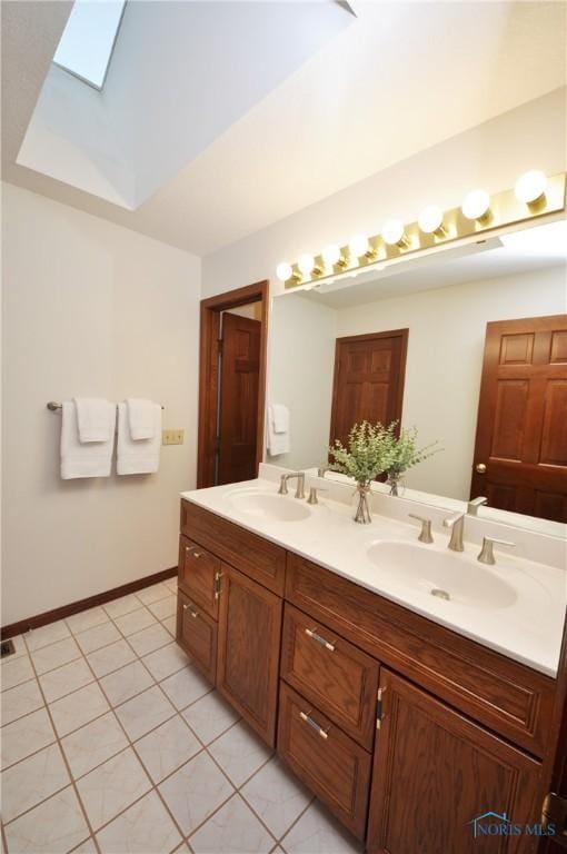 bathroom with tile patterned floors, vanity, a raised ceiling, and a skylight