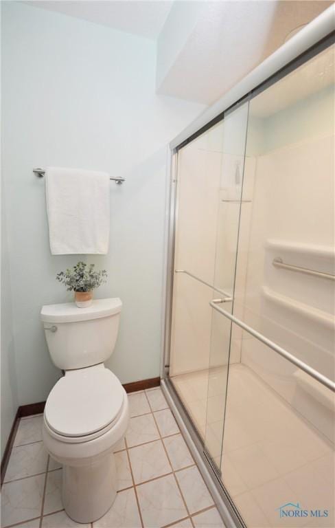 bathroom featuring tile patterned flooring, a shower with shower door, and toilet