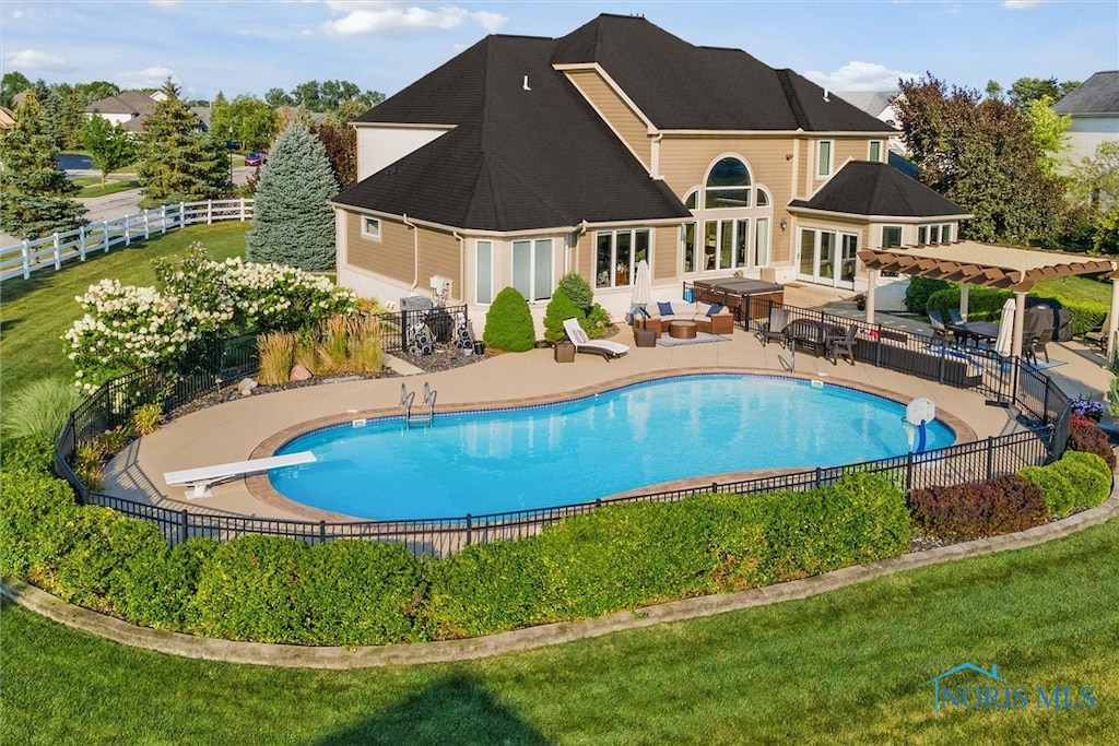 view of pool featuring a yard, a diving board, and a patio