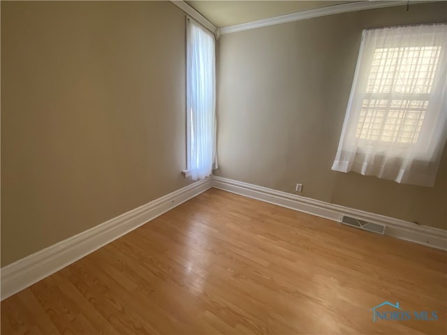 empty room with ornamental molding and hardwood / wood-style floors