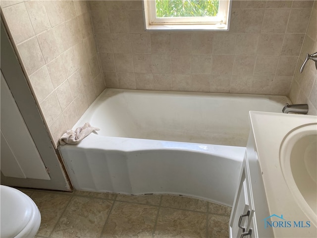 bathroom with a tub to relax in, vanity, and toilet