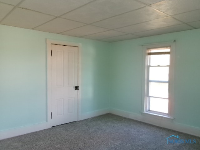 carpeted spare room with a drop ceiling