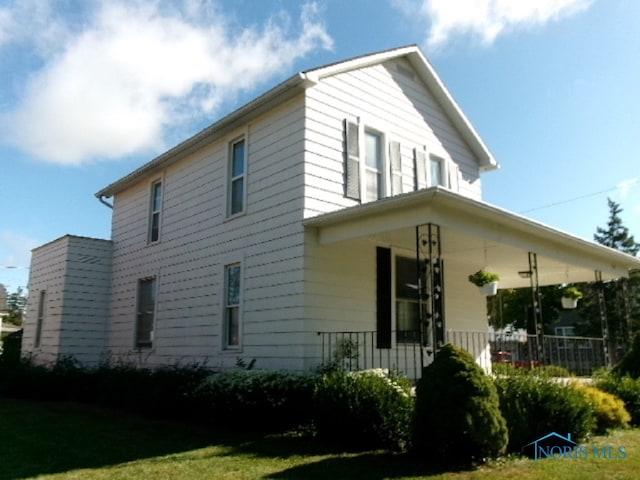 view of home's exterior with a lawn and covered porch