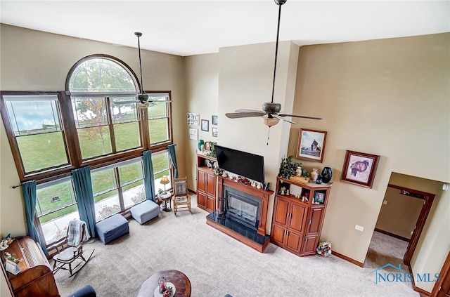 carpeted living room featuring a towering ceiling and ceiling fan