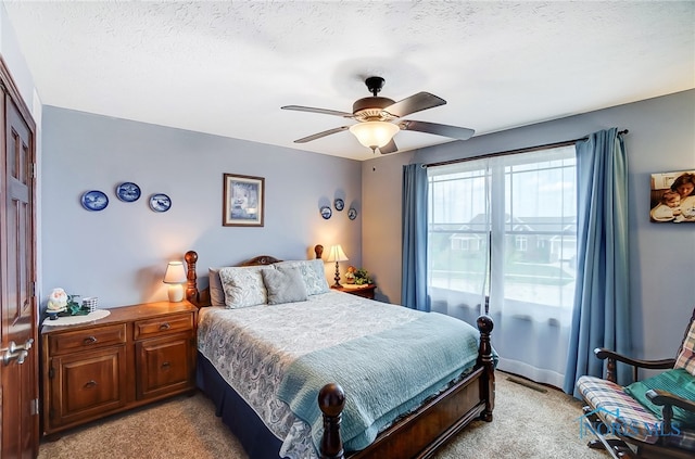 bedroom featuring ceiling fan, light carpet, and a textured ceiling