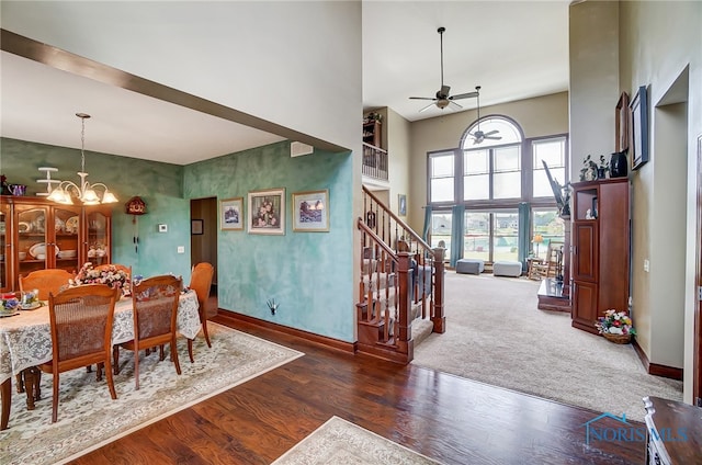 interior space featuring dark wood-type flooring, ceiling fan with notable chandelier, and a high ceiling