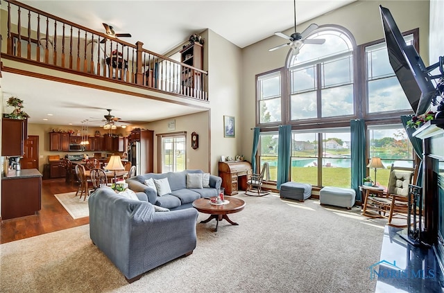 living room featuring dark wood-type flooring, ceiling fan, and a high ceiling