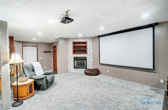 carpeted home theater room with a stone fireplace