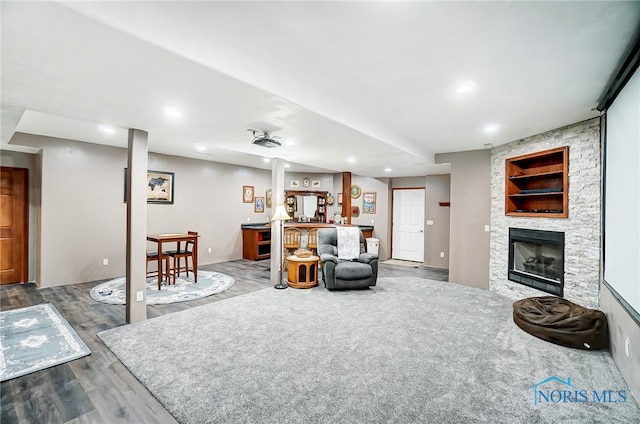 living room featuring bar, a stone fireplace, and hardwood / wood-style flooring