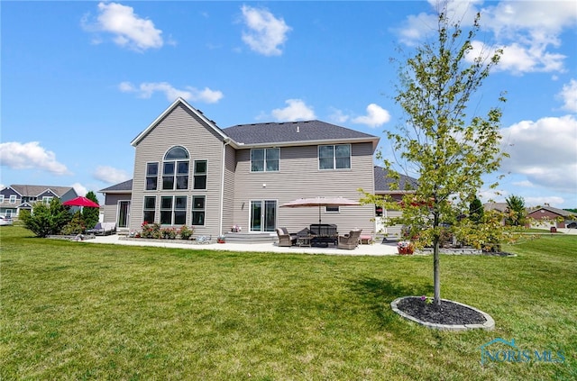 rear view of house featuring a lawn and a patio