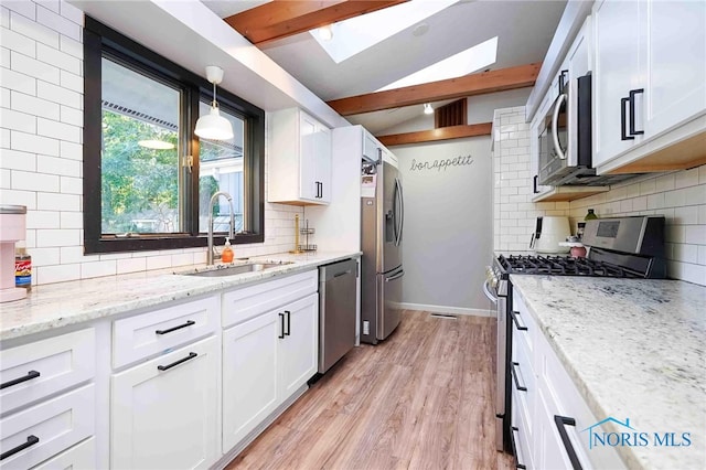 kitchen featuring white cabinets, light wood-type flooring, stainless steel appliances, sink, and pendant lighting