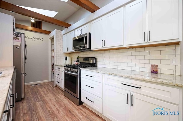 kitchen with hardwood / wood-style flooring, light stone counters, stainless steel appliances, beamed ceiling, and white cabinetry