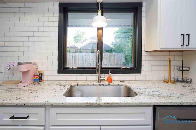 kitchen with white cabinetry, light stone countertops, decorative light fixtures, and sink