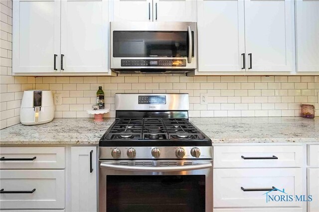 kitchen featuring appliances with stainless steel finishes, white cabinetry, and backsplash