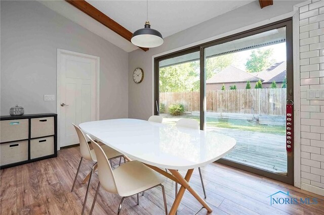 dining space featuring light hardwood / wood-style floors and vaulted ceiling with beams