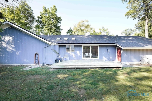 rear view of property featuring a lawn and a deck