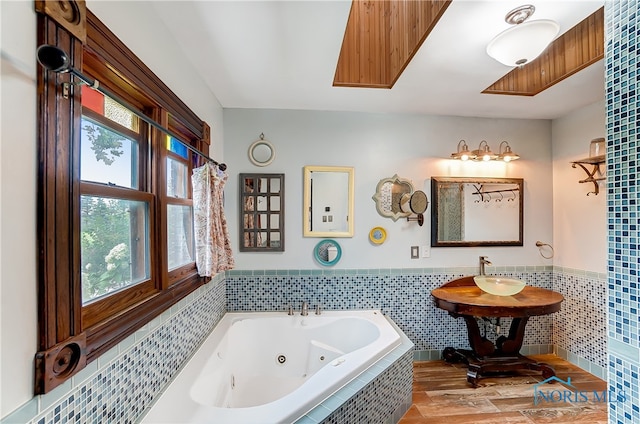 bathroom with tile walls, a relaxing tiled tub, and a healthy amount of sunlight