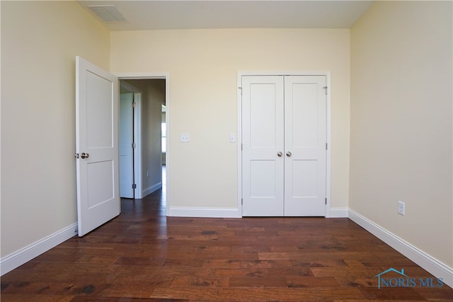 unfurnished bedroom featuring dark wood-type flooring and a closet