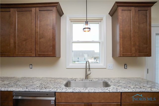 kitchen featuring a wealth of natural light, stainless steel dishwasher, light stone counters, and sink